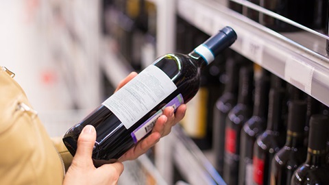 pessoa com garrafa na mão a ver o rótulo para comprar vinho